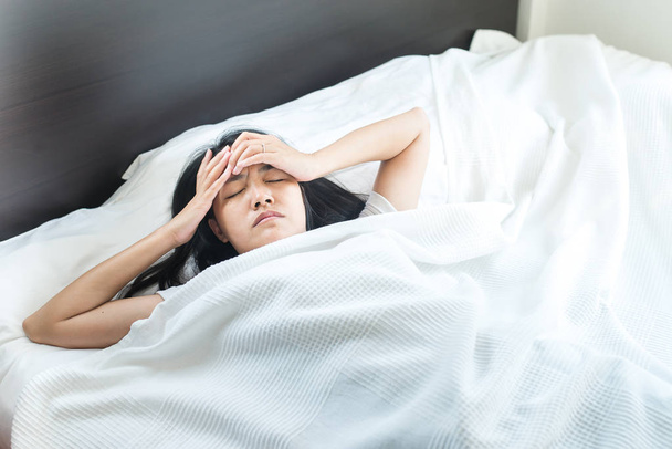 Asian woman have a headache on bed after wake up in the morning - Foto, immagini