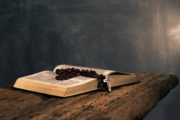 Szent Biblia feszület és gyöngyök egy öreg tölgy fából készült asztal. Gyönyörű sötét háttér előtt. A vallás fogalma - Fotó, kép
