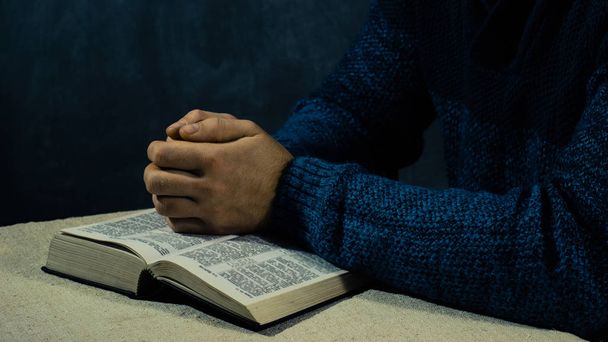 Молодой человек, сидящий за столом и читающий Библию
 - Фото, изображение