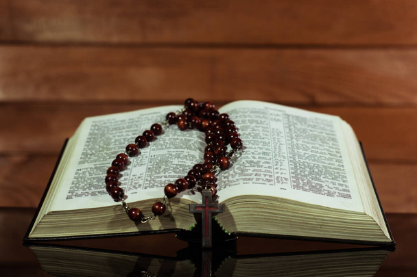Bible and a crucifix on a black glass table. Beautiful background.Religion concept. - Foto, Imagem