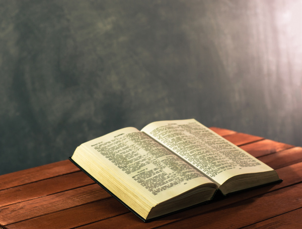 Bíblia em uma mesa de madeira vermelha. Fundo bonito.Conceito de religião
 - Foto, Imagem