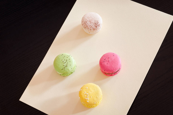 Four multicolored macarons on a yellow paper sheet - Foto, Imagem