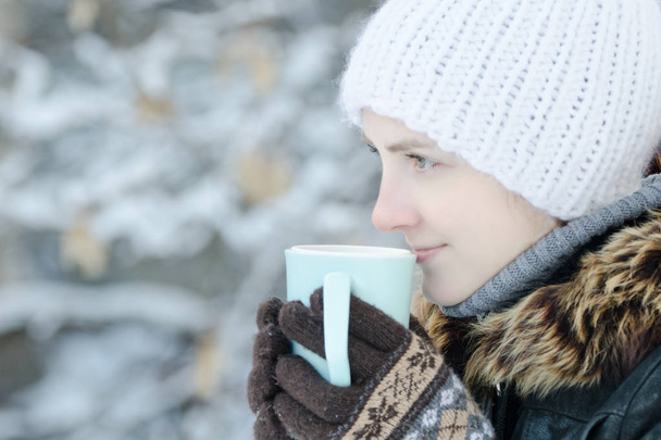 Chica con ropa de invierno bebiendo té de una taza. Vista lateral
 - Foto, imagen
