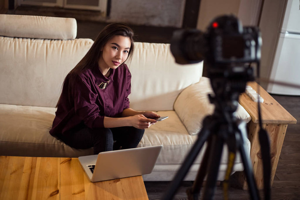 Красива дівчина сидить перед камерою і тримає свій щоденний відеоблог, сидячи на зручному дивані вдома
. - Фото, зображення