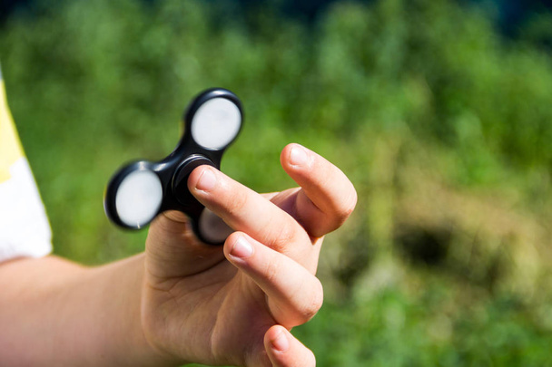 Boy playing with fidget spinner stress relieving toy outdoor - Photo, image