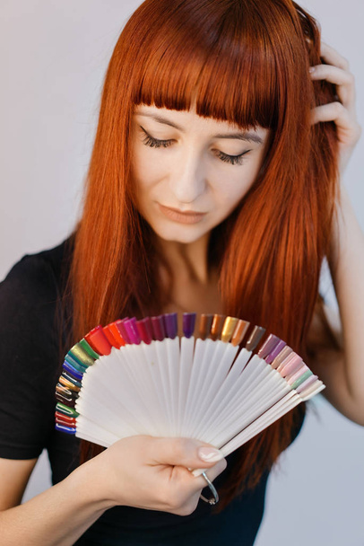 Portrait of a beautiful girl with samples of colored nail polish. Manicurist - Foto, Imagem