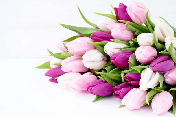 White and pink tulips on white wooden table. Holiday background, copy space - Photo, Image