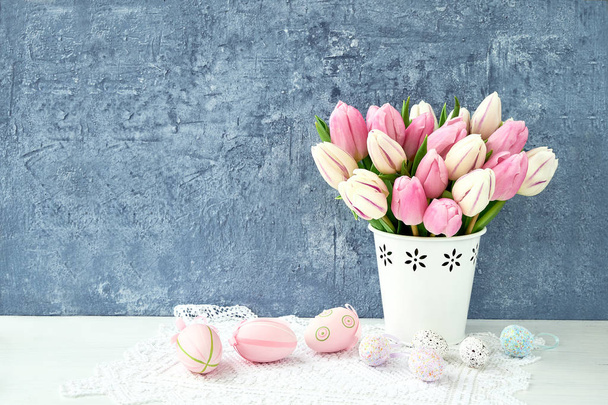 Pasen achtergrond. Decoratieve paaseieren en roze tulpen in de vaas. Kopiëren van ruimte - Foto, afbeelding