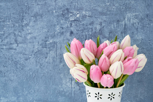 Rosafarbener Tulpenstrauß in weißer Vase auf blauem Hintergrund. Ferienhintergrund, Kopierraum. Valentinstag, Muttertag, Geburtstagskonzept. - Foto, Bild
