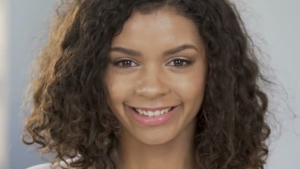 Portrait of cheerful biracial woman applying halves of orange to eyes, optimism - Materiał filmowy, wideo