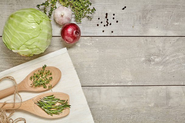 Wooden spoon with Caraway and rosemary, cabbage, onion, garlic on wooden background. Top view. - Valokuva, kuva