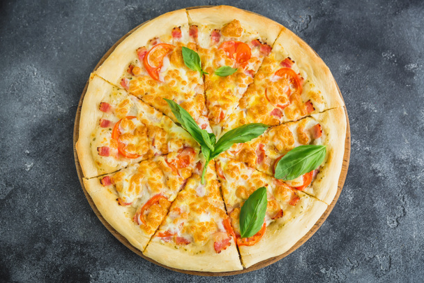 Delicious pizza with bacon, cheese, tomato on dark background. Flat lay, top view. Food background - Photo, Image