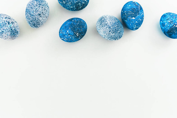 Huevos de Pascua moteados azules sobre fondo blanco. Acostado. Vista superior
 - Foto, Imagen