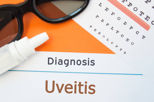 Glasses, eye drops and eye test chart is around inscription Diagnosis Uveitis. Concept photo for causes, diagnosis, treatment and prevention of ophthalmic disease Uveitis - Photo, Image