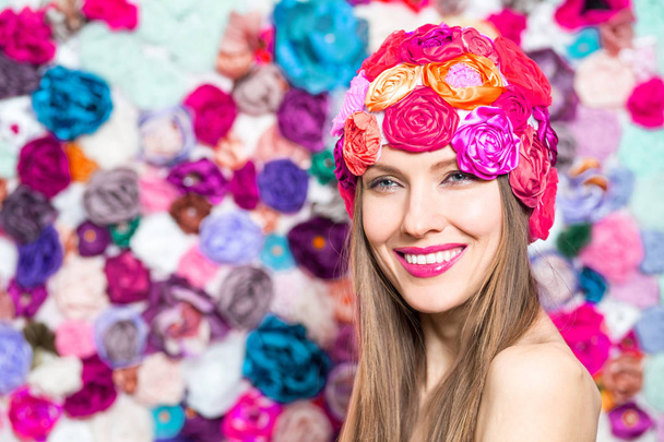 Pretty young smiling woman in hat over floral background - Foto, afbeelding