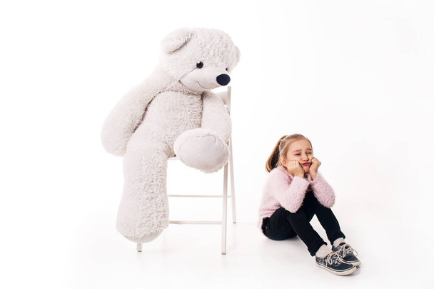 Μικρό κορίτσι και ένα μεγάλο λευκό αρκουδάκι. Απομονωμένα σε λευκό φόντο. - Φωτογραφία, εικόνα
