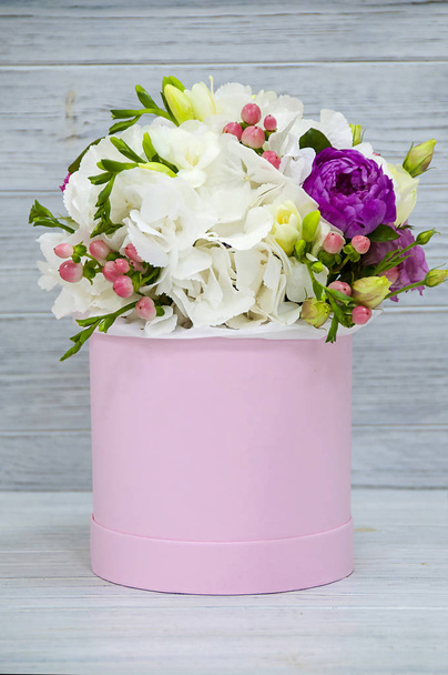 Beautiful tender bouquet of flowers in pink box on light blue woden background  - Fotó, kép