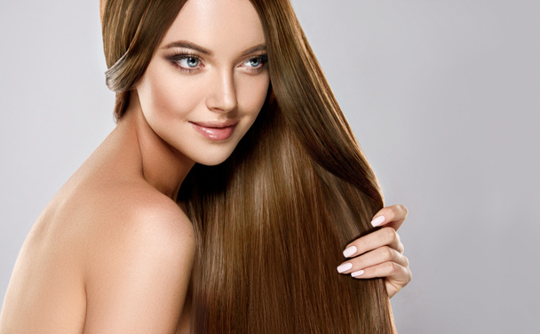 Hermosa chica modelo con pelo largo liso marrón brillante. Productos para el cuidado y el cabello
 . - Foto, imagen
