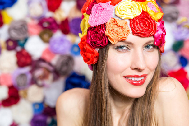 Pretty young smiling woman in hat over floral background - Foto, immagini