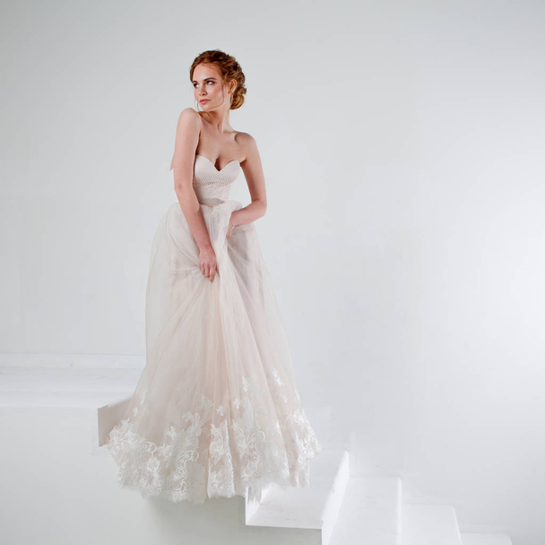 Portrait of a beautiful girl in a wedding dress. Bride in luxurious dress on a white background - Фото, зображення