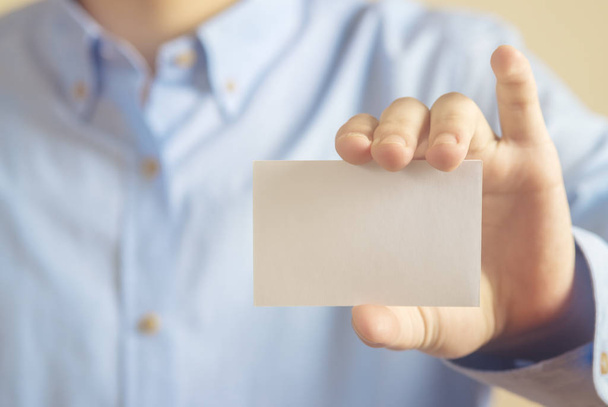 Man holding white business card on concrete wall background - Φωτογραφία, εικόνα