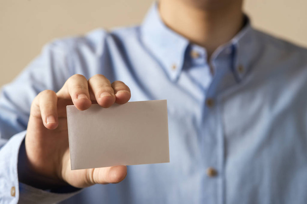 Man holding white business card on concrete wall background - Valokuva, kuva