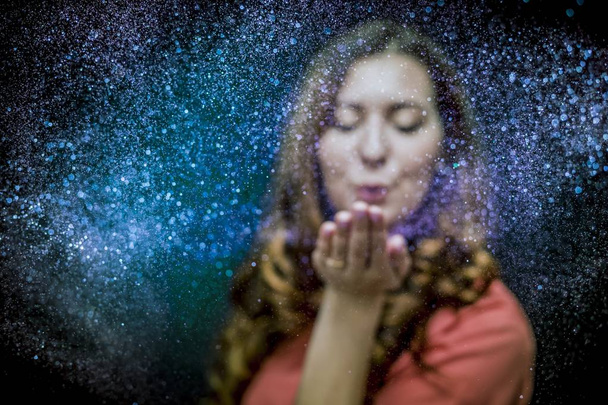 Girl blowing colored glitter from her hand - Foto, afbeelding