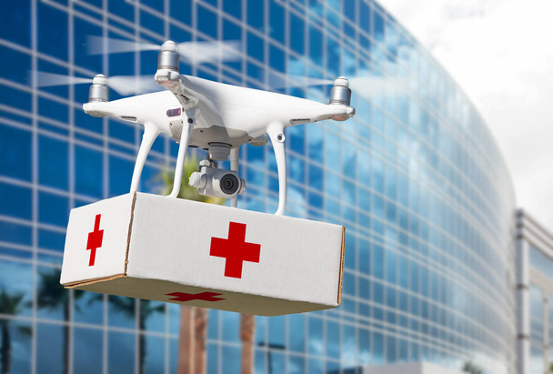 Unmanned Aircraft System (UAS) Quadcopter Drone Carrying First Aid Package Near Corporate Building. - Photo, Image