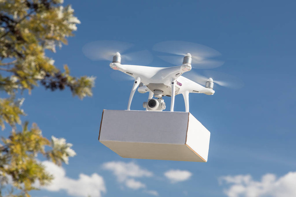 Sistema de aviones no tripulados (UAS) Quadcopter Drone que lleva el paquete en blanco en el aire
. - Foto, Imagen
