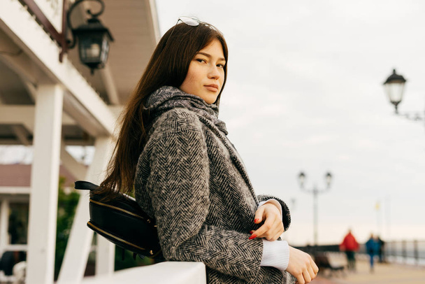 krásná černovlasá dívka v stylový šedý kabát, chodit po městě a pózování - Fotografie, Obrázek
