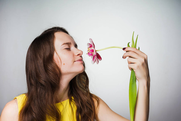 lovely beautiful young woman smelling a fragrant flower, celebrating a world women's day - Zdjęcie, obraz