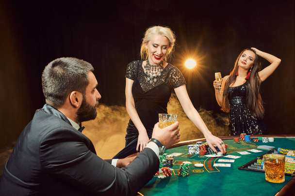 Groep van jonge rijke mensen speelt poker in het casino - Foto, afbeelding