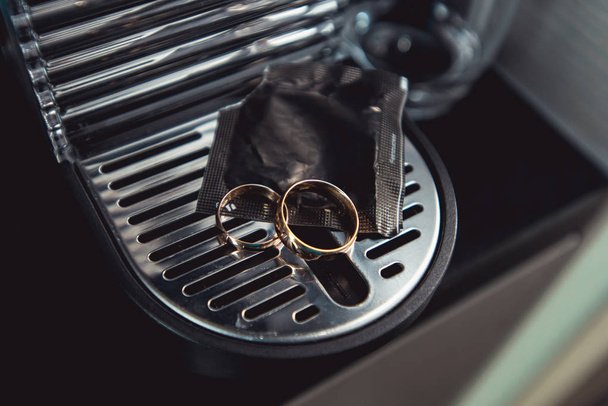 golden wedding rings on a chrome-plated coffee machine - Foto, afbeelding