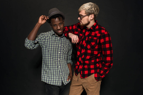 Studio lifestyle portrait of two best friends hipster boys going crazy and having great time together. On black background. - Photo, image
