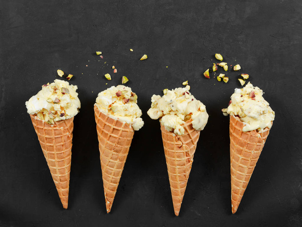 Four ice cream in waffle cone with nuts on black - Photo, Image