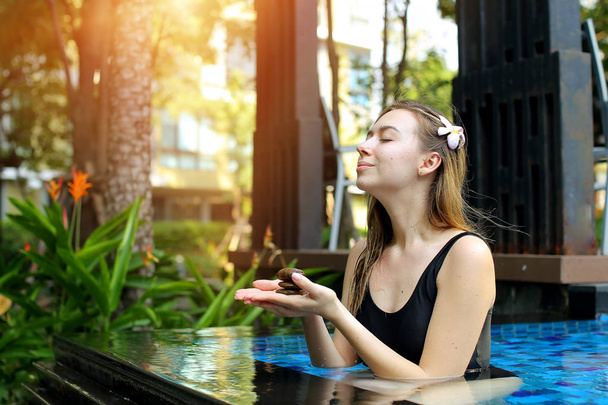 pretty woman holding cairn group of stones, balance in swimming pool sunlight - Foto, imagen