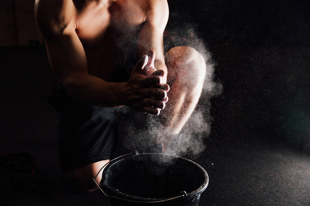 Fitness model trainer rubs his hands with chalk and talc so that fingers do not slip or slide. - Foto, immagini