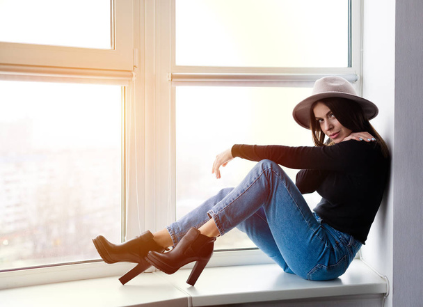 Beautiful boho woman in wool hat sitting by the window - Photo, image