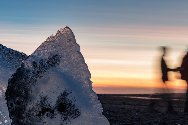 formación de hielo en la playa de Diamond al atardecer con gente moviéndose
 - Foto, imagen