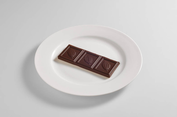 Круглое блюдо с плиткой тёмного шоколада
 - Фото, изображение