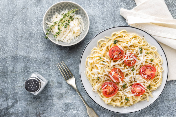 cooked noodles on a table in a plate with tomatoes, parmesan cheese and spices - Photo, Image