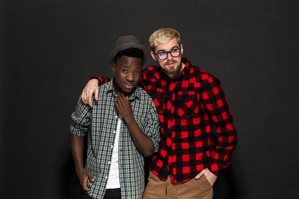 Studio lifestyle portrait of two best friends hipster boys going crazy and having great time together. On black background. - Fotó, kép