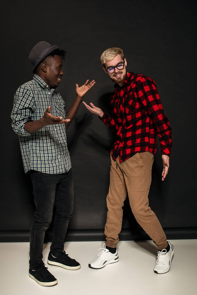 Studio lifestyle portrait of two best friends hipster boys going crazy and having great time together. On black background. - Foto, Imagem