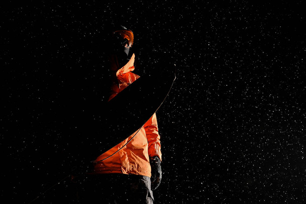 Bottom view of darkened figure of a male snowboarder with a snowboard - Foto, Bild