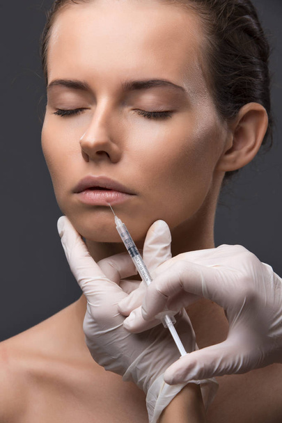 Portrait of young Caucasian woman getting cosmetic injection - Фото, изображение