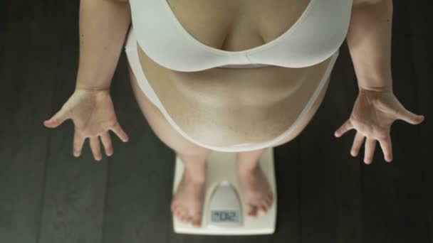 肥満女性の上に立ってスケール必死にジェスチャーの手、太った腹、トップ ビュー - 映像、動画