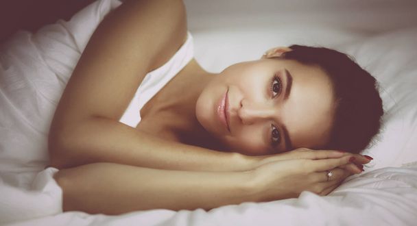 Young beautiful woman lying in bed at home - Photo, Image
