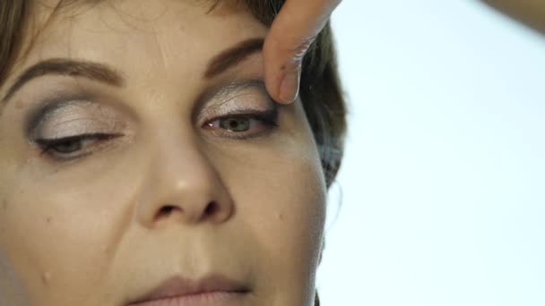 Close-up of professional make-up artist applying eyeliner on eyelid. Stylist is doing make up for female by eyeliner - Πλάνα, βίντεο