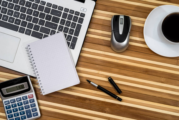 Büroarbeitsplatz - Laptop, Kaffee, Stift und Taschenrechner, Notizblock - Foto, Bild