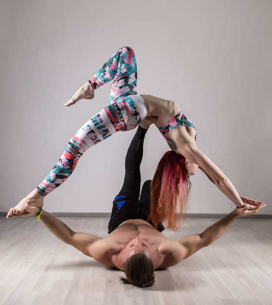 sports man and woman doing acroyoga exercises in a dark room - Photo, image